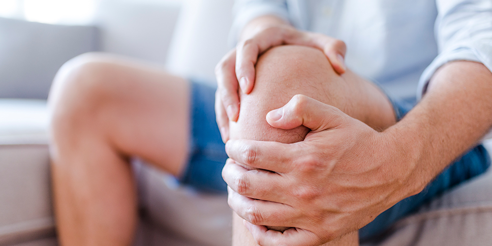 Man clutching knee in pain