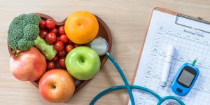 Blood sugar tracker and bowl of healthy fruits and vegetables